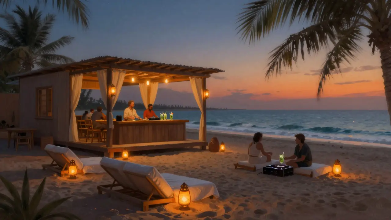 Relaxed beach lounge at The Beach House with lanterns, sand, and ocean waves at dusk.
